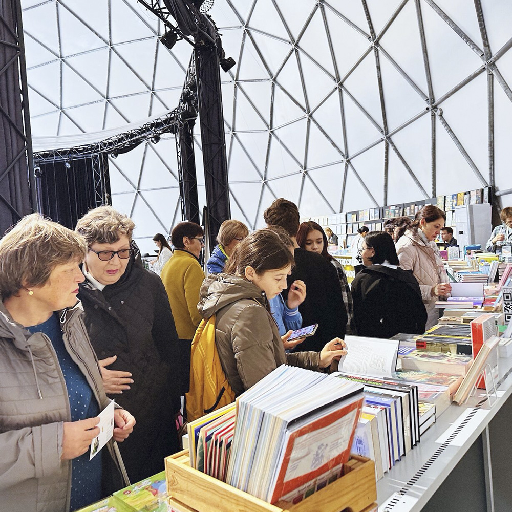 Посетители у прилавков с детскими книгами на ярмарке фестиваля «Мы и Менделеевск»