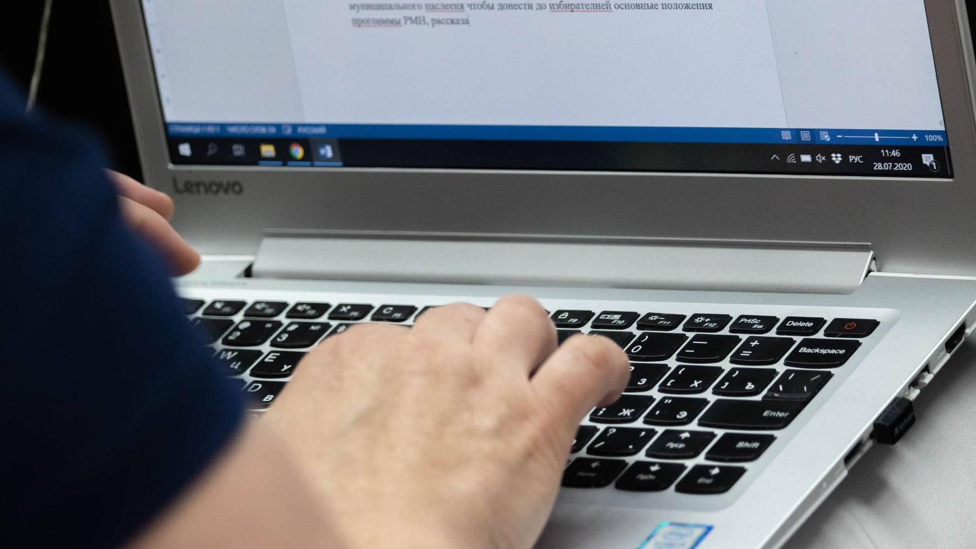 Рука печатает на клавиатуре ноутбука Lenovo