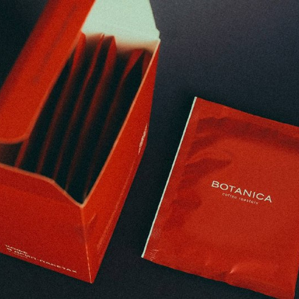 Красная коробка с дрипами Botanica и «Кофе от «Нефти»» на темном фоне